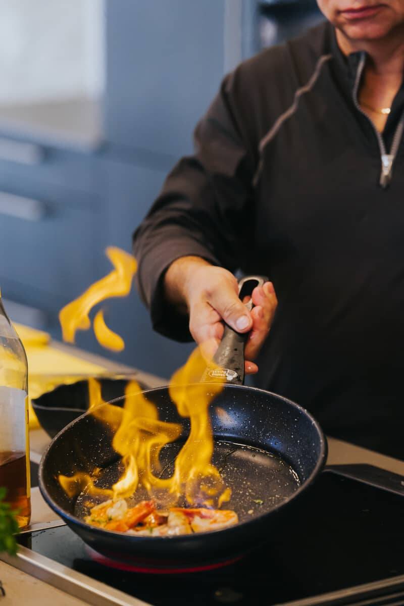 Eine Nahaufnahme einer Pfanne, in der ein Gericht flambiert wird.