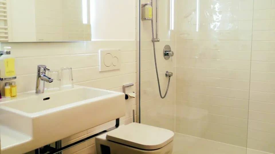 Ein Badezimmer mit Waschbecken, Spiegel, Toilette und Dusche mit Glaswand.