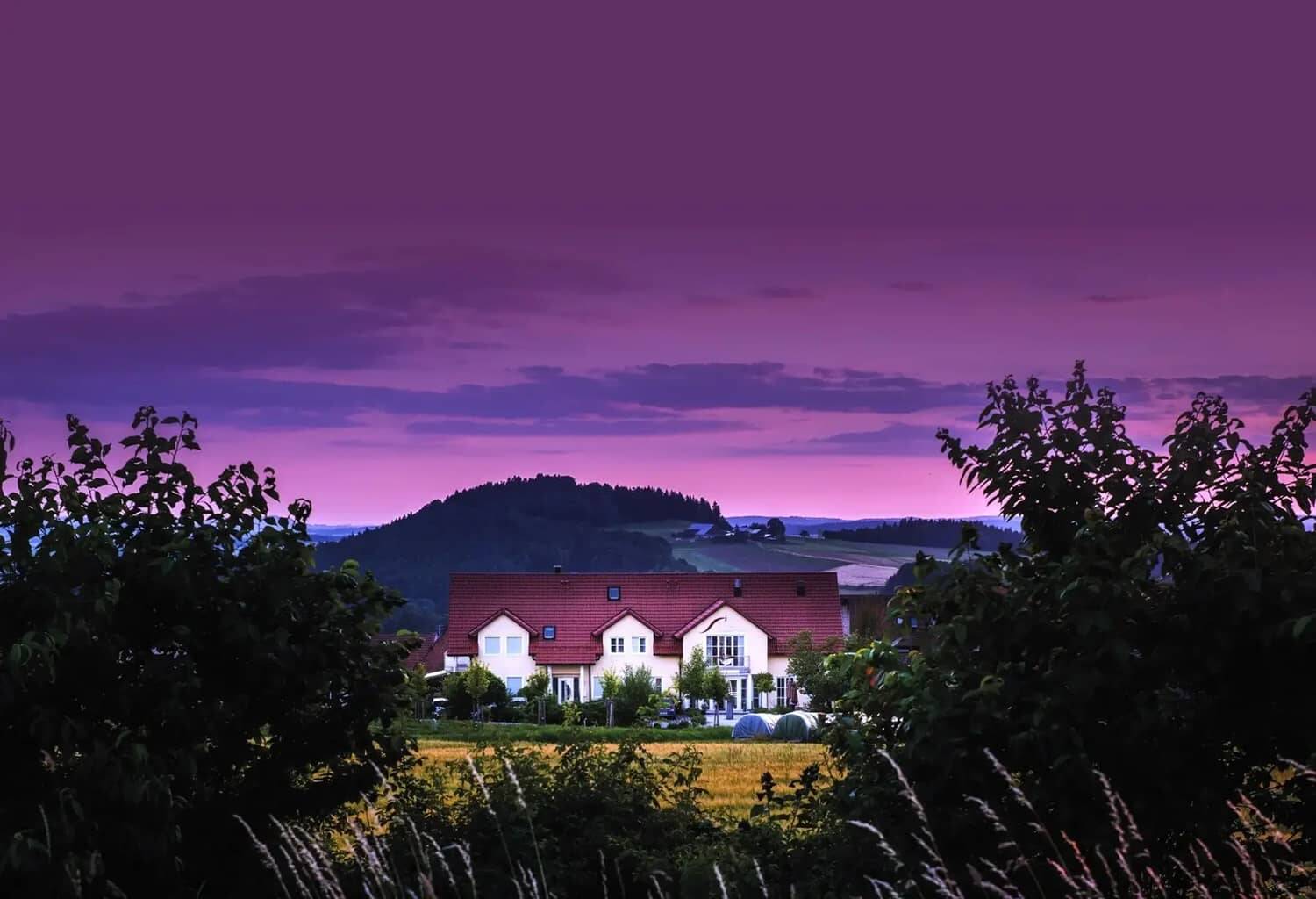 Das Tagungshotel Hollerhöfe aus der Ferne fotografiert, mit violettem Himmel in der Abenddämmerung.