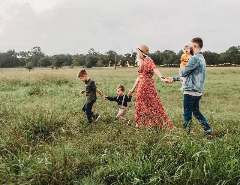 A family with three small children walking hand in hand through a green meadow - an example of a wide range of family activities during a holiday in the Upper Palatinate.