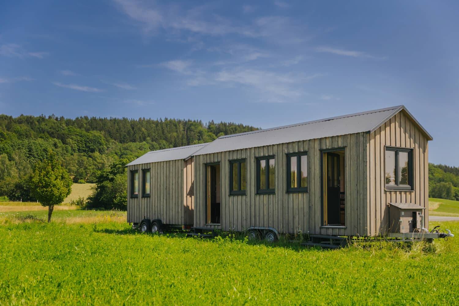 Modern wooden Tiny House on a green meadow, surrounded by nature and trees in the background. The Tiny House is part of the Hollerhöfe as a special conference room in the Upper Palatinate.