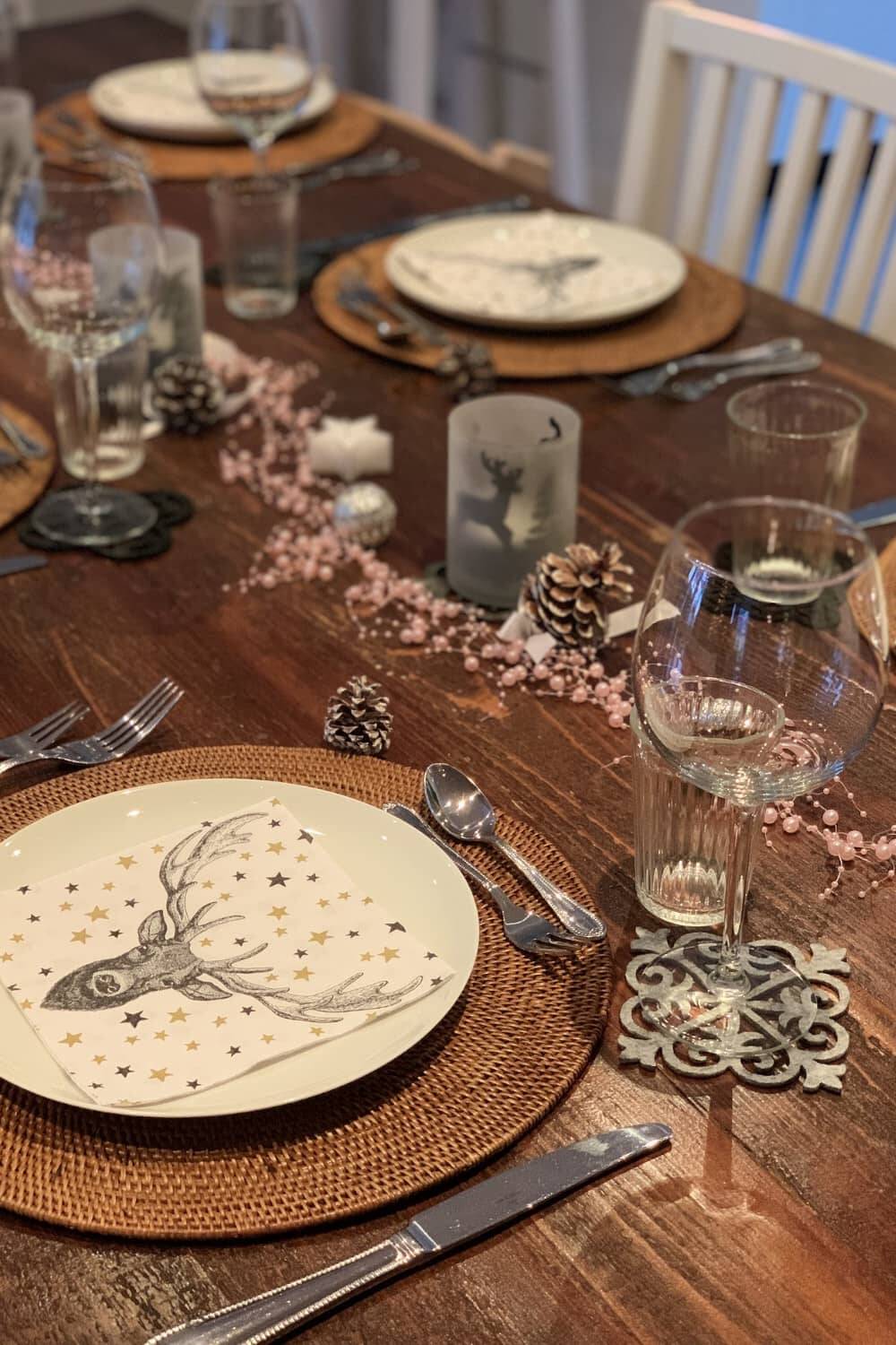 Festlich gedeckter Tisch für eine Weihnachtsfeier mit Tannenzapfen, Kerzen und schlichter, aber stilvoller Weihnachtsdeko.