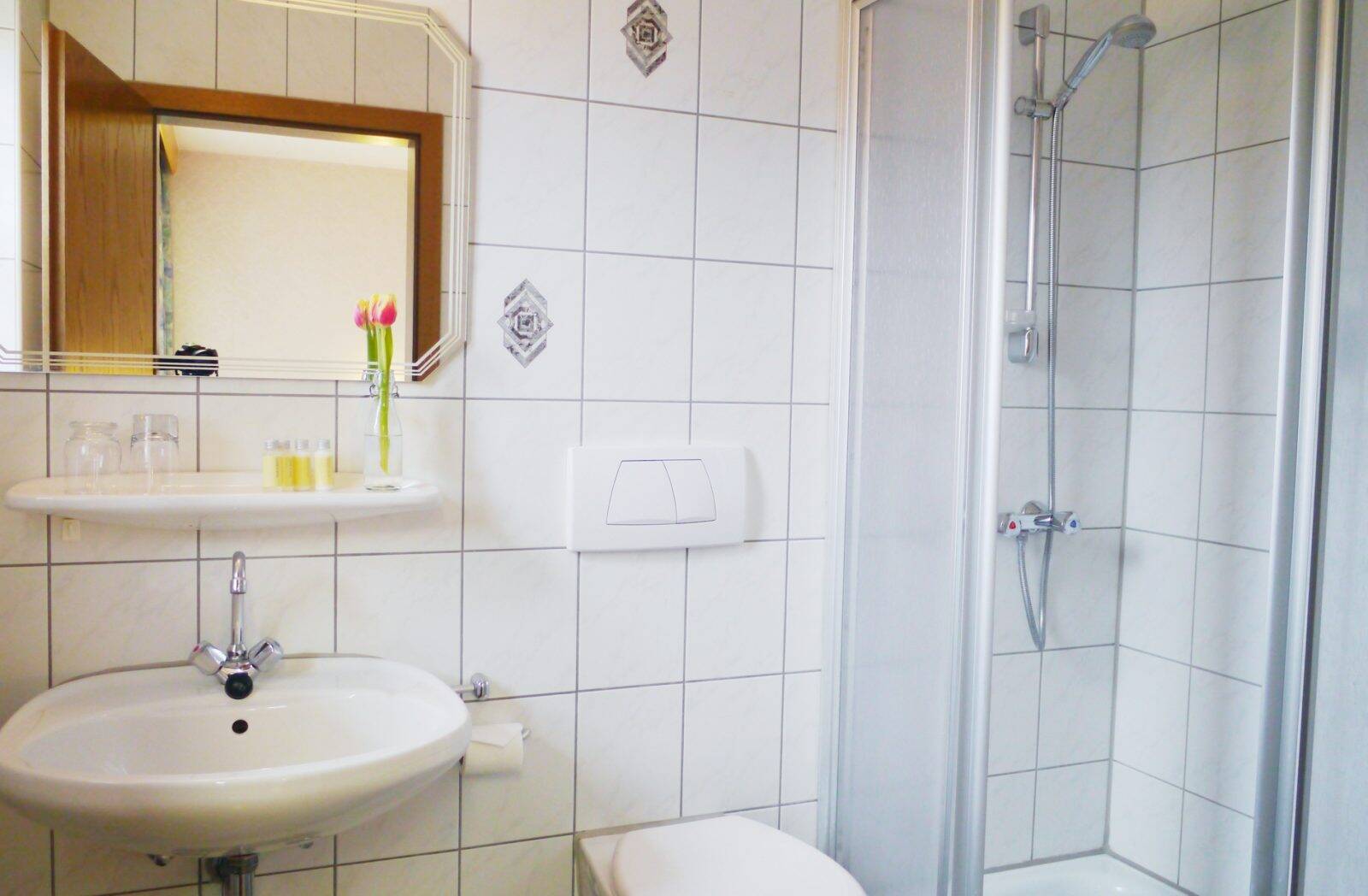 Das Badezimmer mit WC, Dusche und Waschbecken mit Spiegel und Kosmetikartikeln.