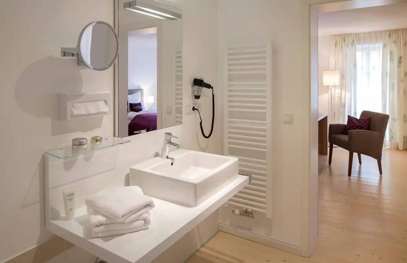Ein modernes Badezimmer in dem Hotel in Kemnath: mit viereckigem Waschbecken, Spiegel, Föhn und Handtüchern auf der Anrichte.