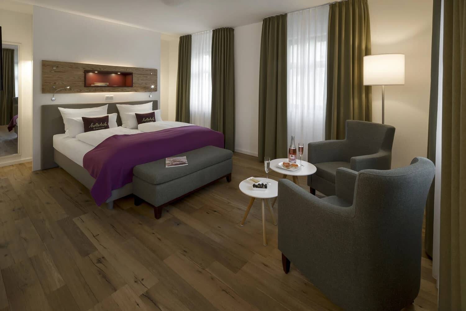 Das Schlafzimmer im 1-Raum-Apartment mit Bett und zwei Sesseln als Sitzgelegenheit.