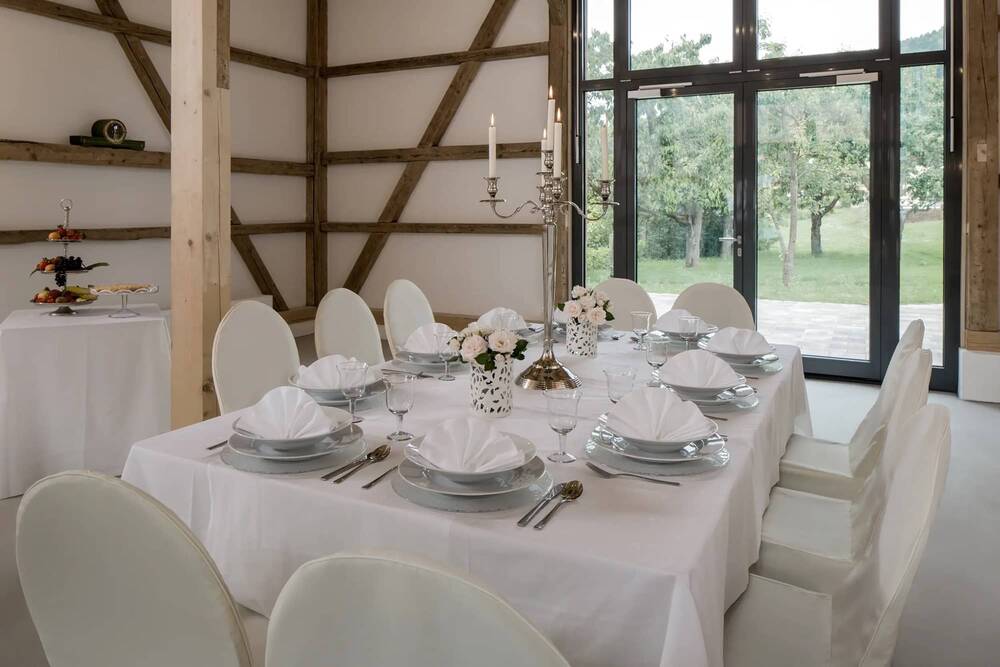Ein in weiß festlich gedeckter Tisch in der Eventlocation Hollerhöfe.