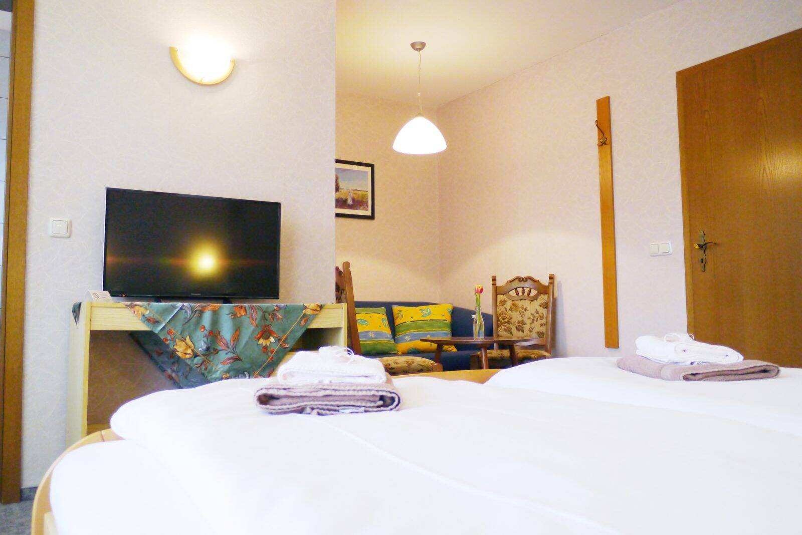 Der Blick vom Bett in Richtung Fernseher und einer kleinen Sitzecke im Zimmer.