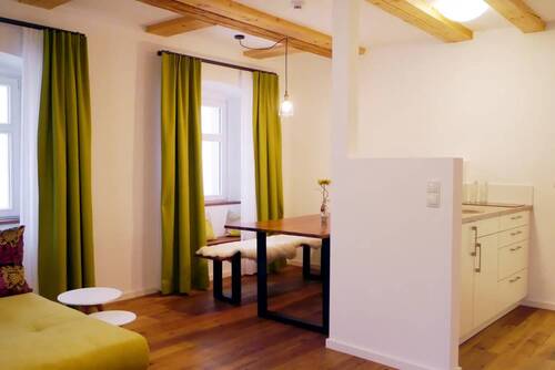 The living area in the Kösslerhaus with a view of the kitchenette and behind it on the left, separated by a wall, a dining alcove with a wooden table.