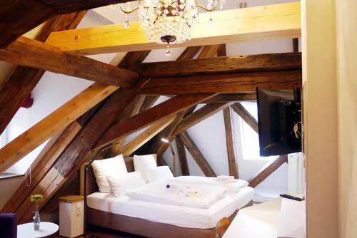 The bedroom in the Kösslerhaus with a view of the bed and the many rustic wooden beams in the ceiling.