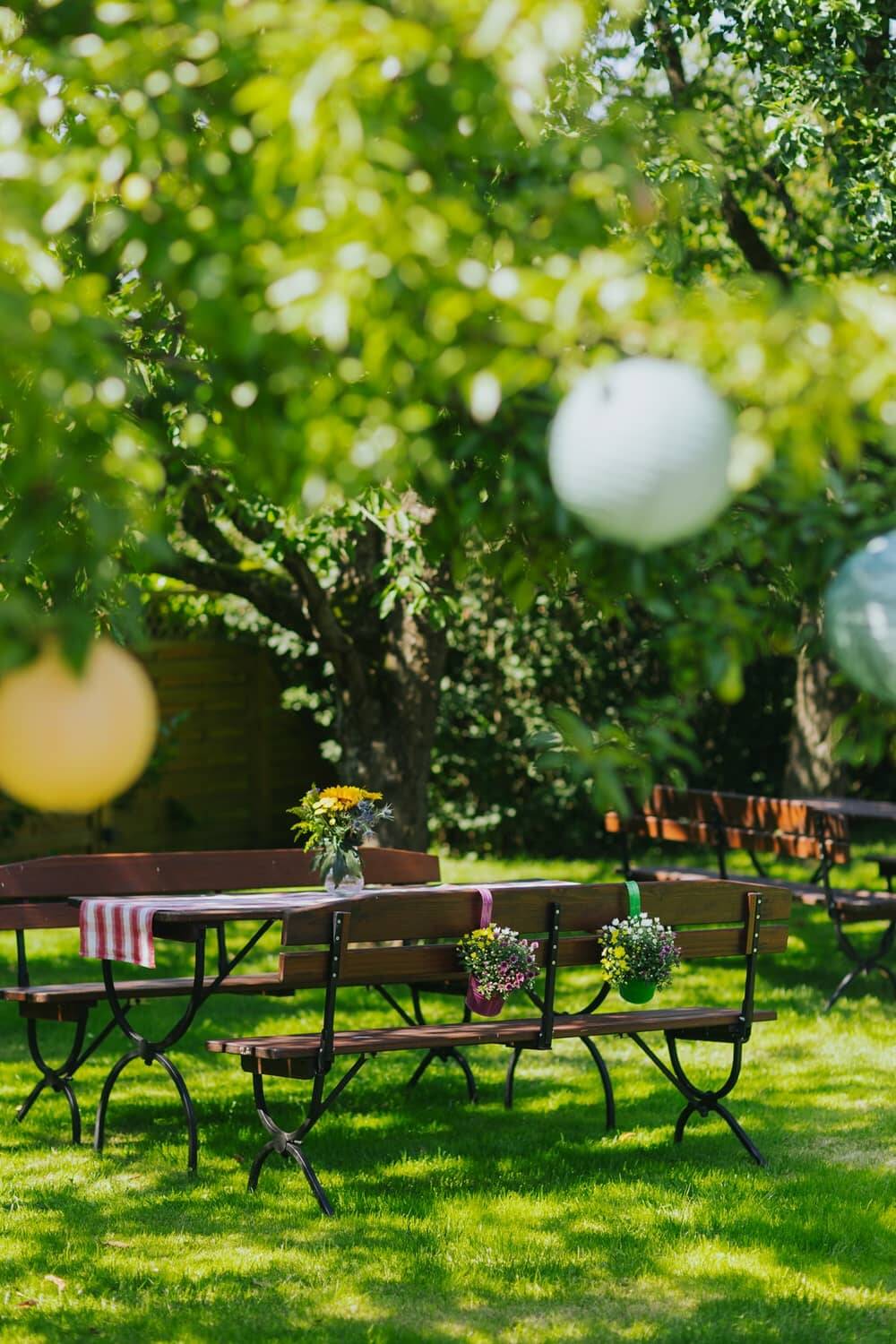 Ein liebevoll gedeckter Gartentisch unter einem blühenden Baum als Sinnbild für die Hollerhöfe als Eventlocation mit Garten.