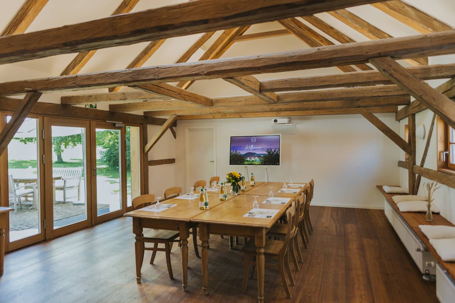 The Hollermanufaktur with conference table, terrace and view of the greenery at the Hollerhöfe conference hotel.