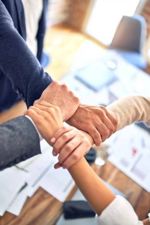 Four hands, each gripping the next by the wrist to form a square - the photo symbolises team building and cohesion.