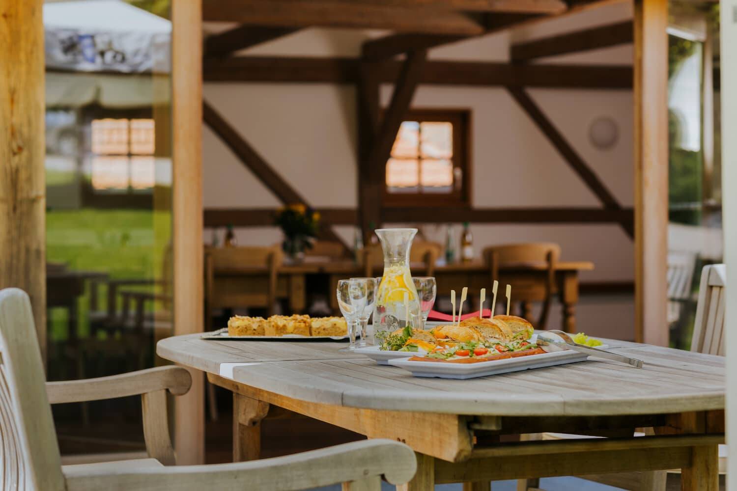 Wooden table set on the Hollermanufaktur terrace with tasty snacks and a refreshing drink - an example of the conference catering at the Hollerhöfe.