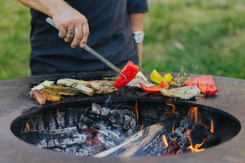 Fleisch, Bratwürste und Grillgemüse auf einer Feuerschale im Garten – Grillabend in den Hollerhöfen Waldeck
