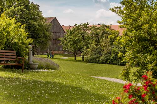 Grüner Garten mit Obstbäumen, Holzscheune und Kiesweg in Waldeck – Veranstaltungsgelände der Hollerhöfe beim Ewilpa-Jubiläum 2026