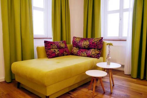 A green couch with two white side tables in one of the Hollerhöfe holiday homes.