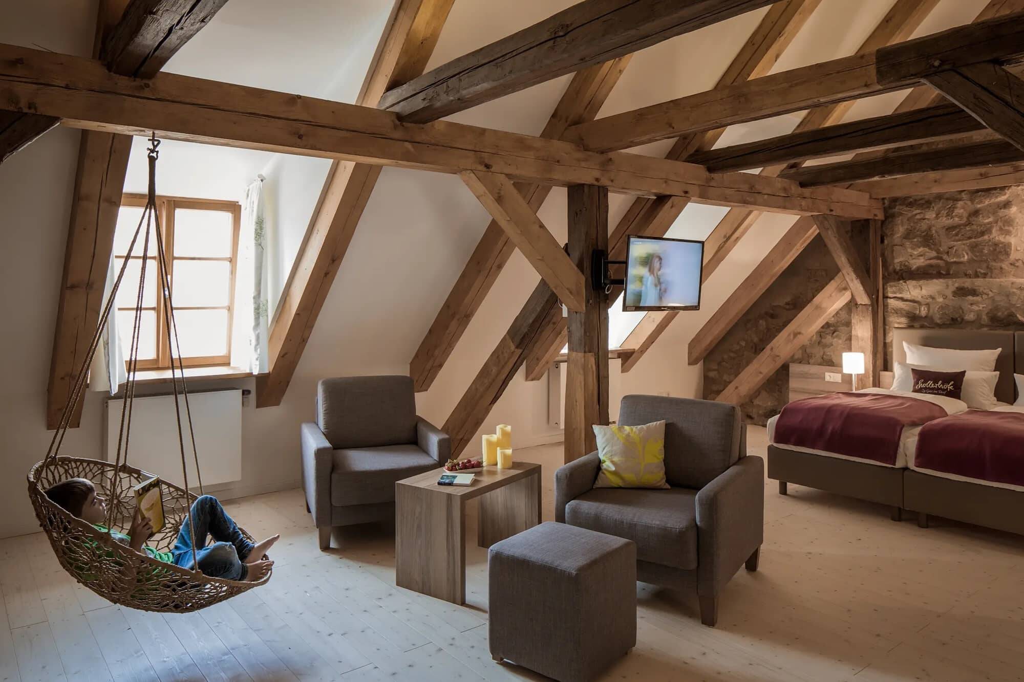 The bedroom and living room in the Schreiberhaus with hanging chair and lounge as an inviting holiday home in Bavaria.