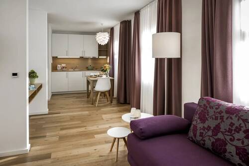 The living room with purple sofa, small dining table and kitchenette in one of the Hollerhöfe holiday flats.