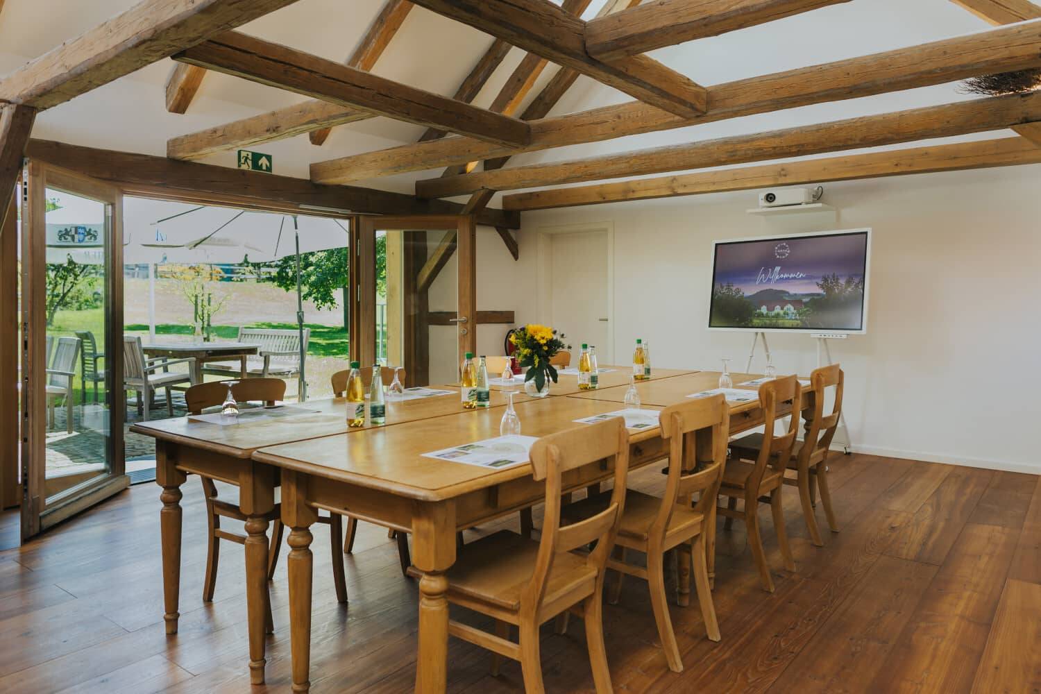 The conference table in the Hollermanufaktur with wide-open patio doors and a view of the greenery.