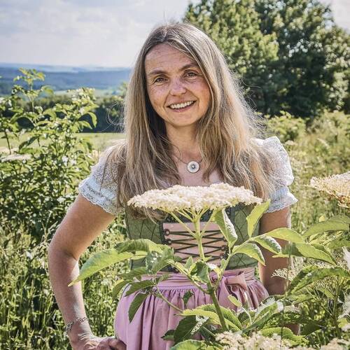 Die Gastgeberin Elisabeth Zintl, freundlich lächelnd inmitten eines Hollerfelds.