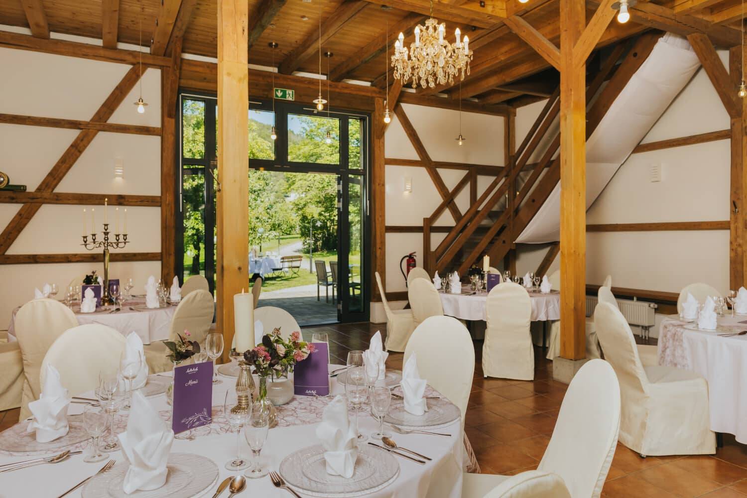 The Hollerscheune as a wedding location with round tables, white tablecloths and festive table settings.